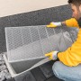 Mann montiert Schellenberg Lichtschachtabdeckung aus Aluminium (50x125cm) am Kellerschacht.