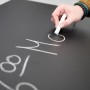 Vasner Infrarotheizung Citara T Tafelheizung: Hand schreibt mit Kreide auf die schwarze Heizungstafel.