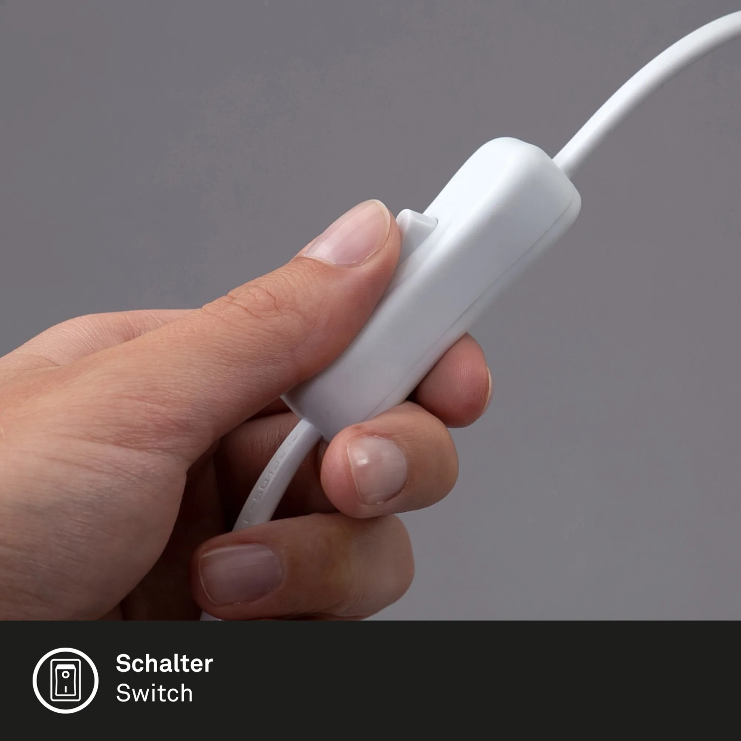 Detailaufnahme: Hand betätigt Kabelschalter der weißen Brilo Tischleuchte Teepu.
