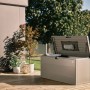 Biohort StyleBox 140 Quarzgrau-Metallic, offener Deckel mit Gasdruckfeder, auf Holzterrasse. Regenwasserdichte Universalbox.