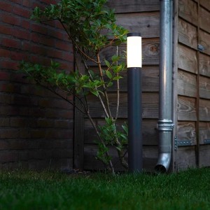 Anthrazitfarbene QAZQA Außenlaterne Rox, 80 cm hoch, neben einer Pflanze im Garten.