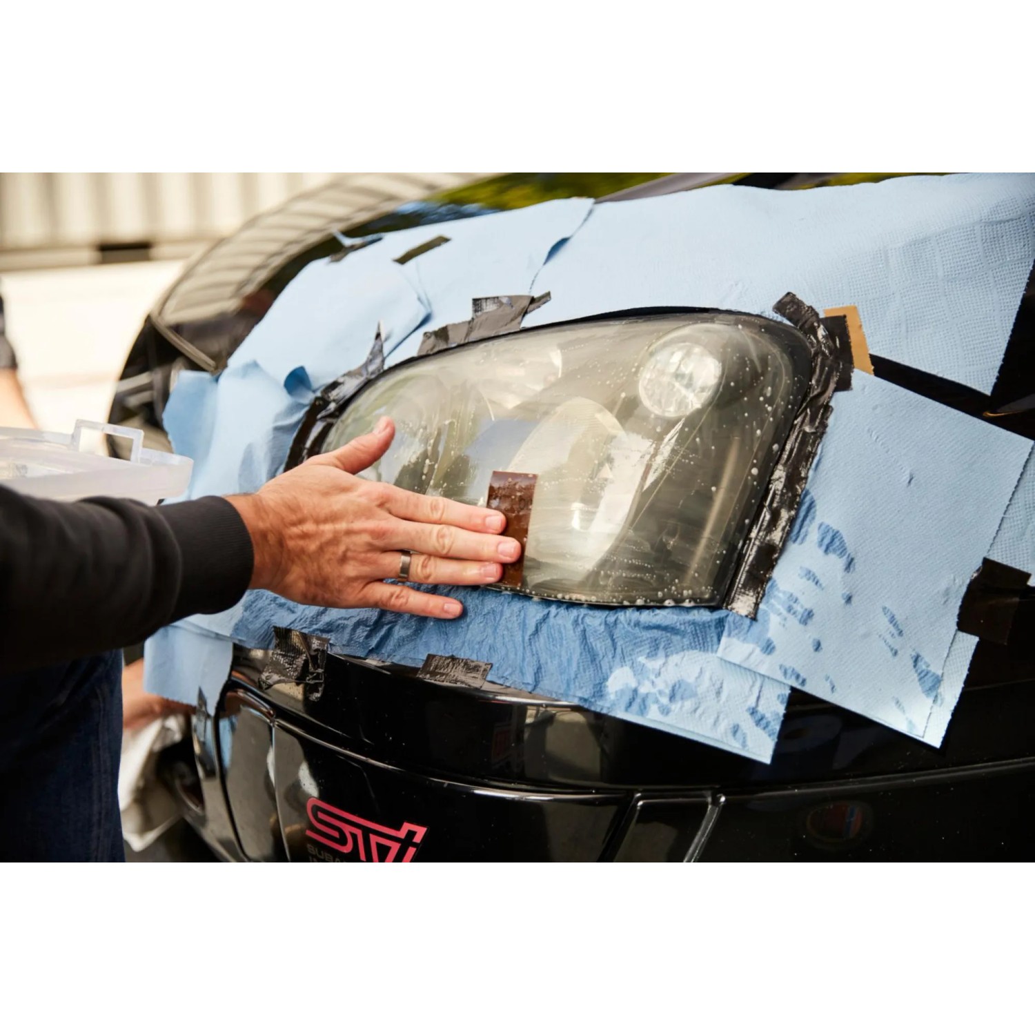 Anwendung von Nigrin Universal-Papier zur Reinigung eines Autoscheinwerfers.