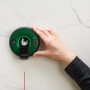 Bosch Atino Linienlaser haftet an Wand und projiziert rote Laserlinie. Prüfwerkzeug für exaktes Ausrichten.