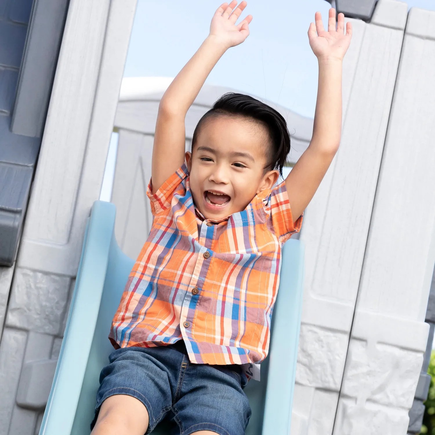 Kind rutscht auf der Rutsche des Step2 Spielhaus Adventures 2-Etagen mit erhobenen Armen.