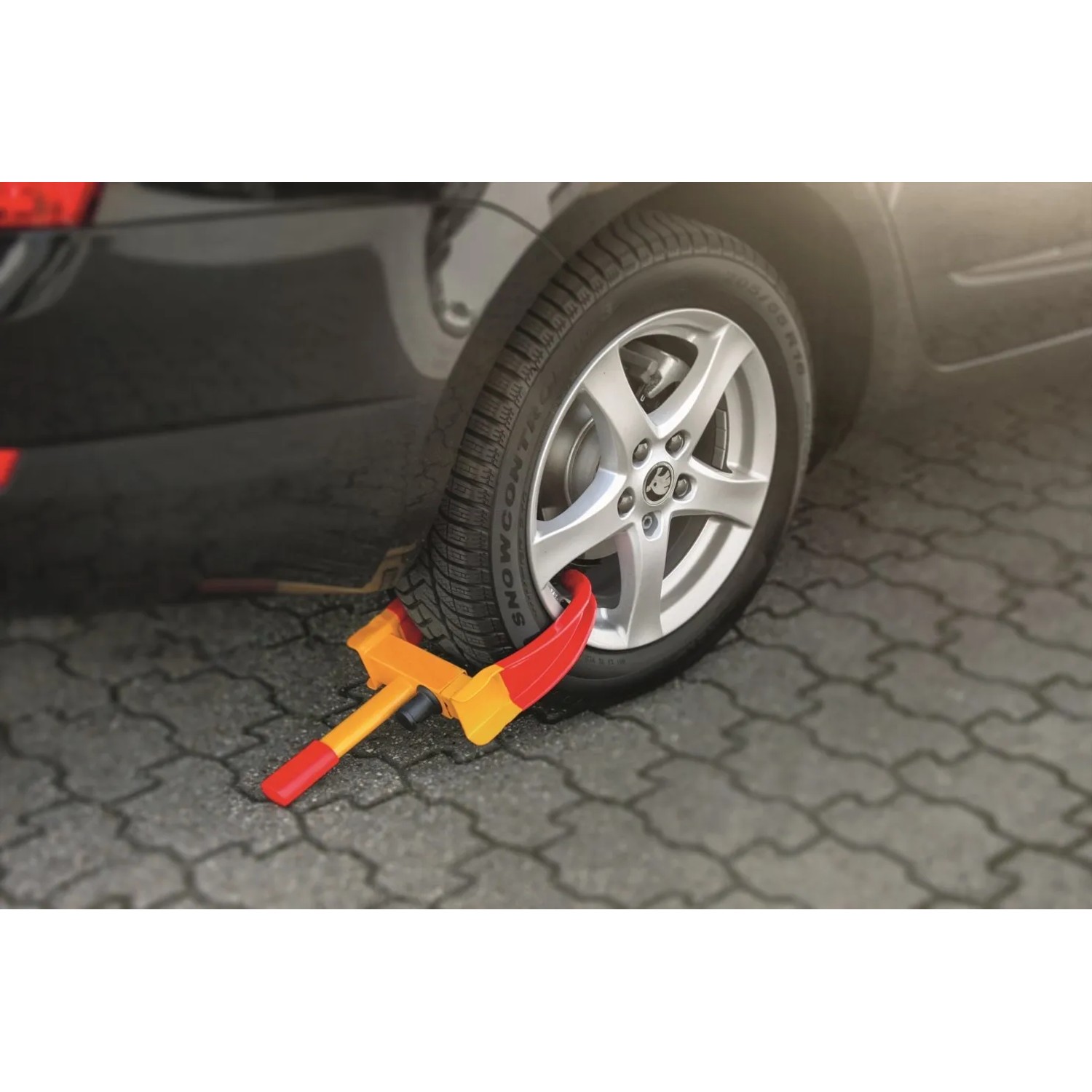 Basi Radkralle am Reifen eines Autos. Universelle Diebstahlsicherung in Rot/Gelb mit 2 Schlüsseln.