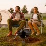 Schwarzer Relaxdays Kugelgrill aus Stahl mit Grillzange, tragbar, im Einsatz beim Camping mit Zelt.