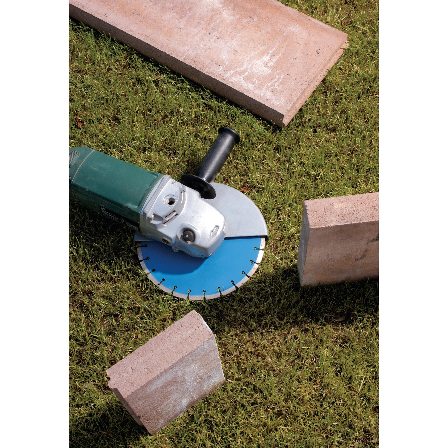 LUX Diamant-Trennscheibe 230 mm mit Winkelschleifer auf Rasen mit Steinen.