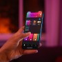 Hand steuert Philips Hue Leuchte Surimu per App. Smarte Lichtsteuerung mit vielen Farben.