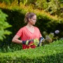 Frau schneidet Hecke mit Ryobi Elektro-Heckenschere RHT4550HS 50 cm.