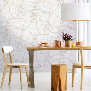 Szene mit Vliestapete KINTSUGI GOLD an der Wand, kombiniert mit Möbeln in Goldtönen.