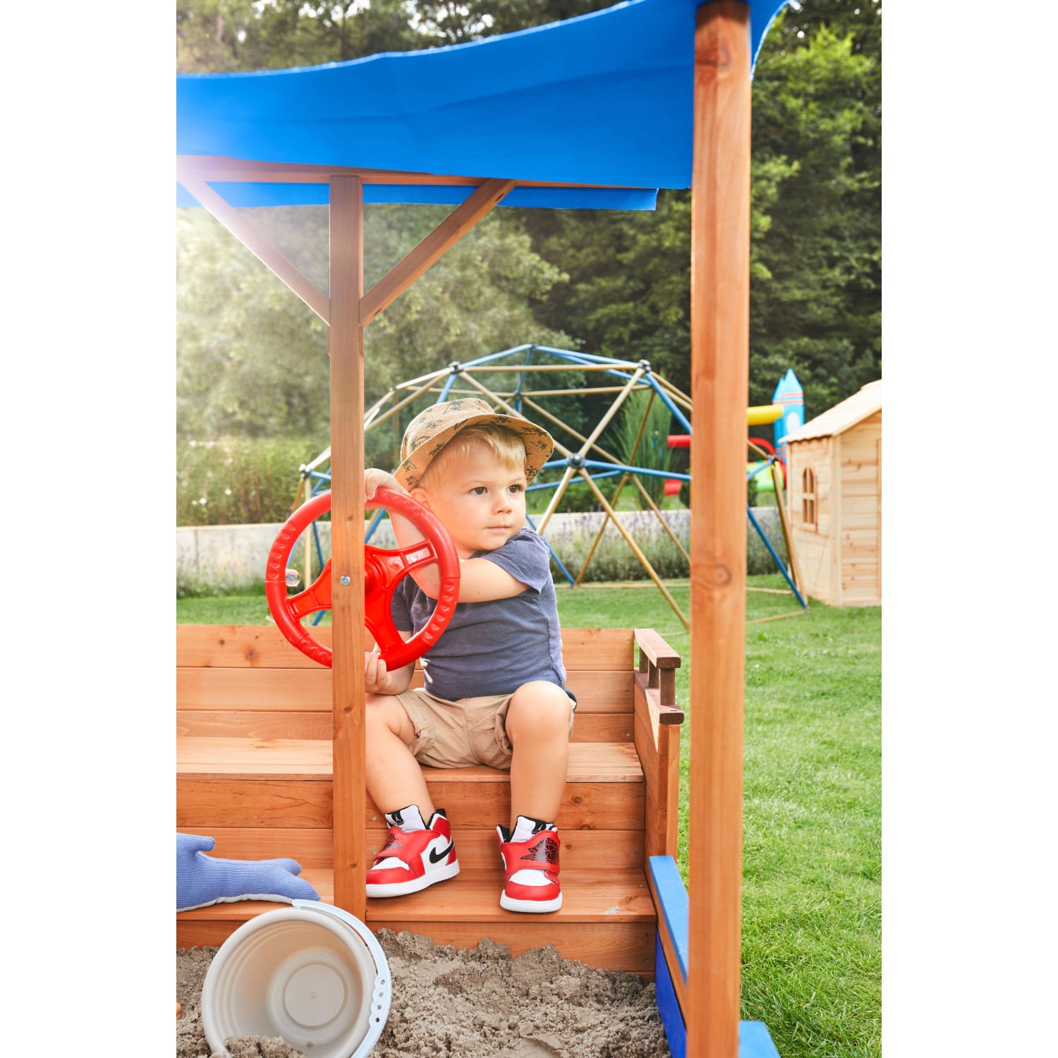 Kind im Home Deluxe Sandkasten Schiff mit Dach und Steuerrad. Sandkiste für den Garten.