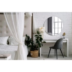 Großer runder Wandspiegel über weißem Schminktisch im Schlafzimmer. Klares Design, reflektiert ein Fenster.