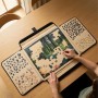 Person puzzelt auf schwarzem, beigem Relaxdays Puzzlekoffer mit Sortierfächern auf Holztisch. Rutschfeste Puzzleunterlage mit Tragegriff.