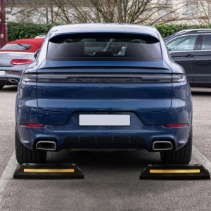 Zwei schwarze Gummi Radstopper mit gelben Reflexstreifen als Einparkhilfe für ein blaues Auto auf dem Parkplatz.