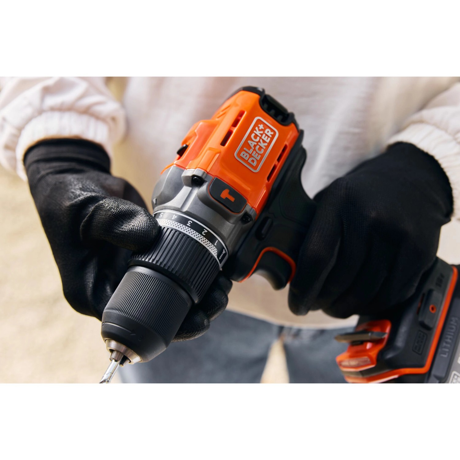 Black+Decker Akku-Schlagbohrschrauber BCD383 in Aktion, gehalten von Person mit Handschuhen.