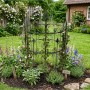 Anthrazitfarbenes Metall-Rankgitter mit Zierspitzen für Kletterpflanzen. Dekorative Rankhilfe im Gartenbeet.