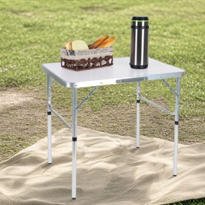 Weißer Relaxdays Campingtisch aus Aluminium, klappbar und höhenverstellbar, auf einer Decke im Gras für Picknick.