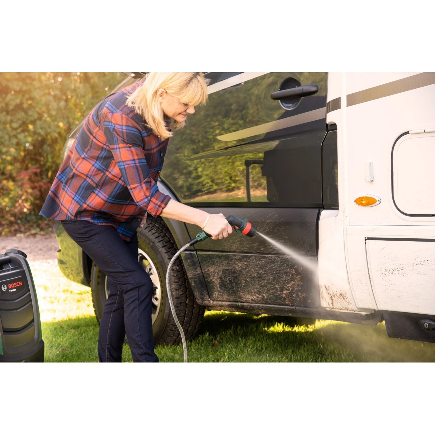 Frau reinigt Wohnmobil mit Bosch Akku-Druckreiniger Fontus 18V. Mobiler Hochdruckreiniger im Einsatz.