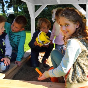 Kinder spielen im Sandkasten des Axi Spielhaus Romy Braun/Weiß mit Rutsche Lindgrün FSC®.