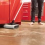 Kärcher Akku-Besen KB 5 im Einsatz auf Holzboden vor roter Küchenzeile.