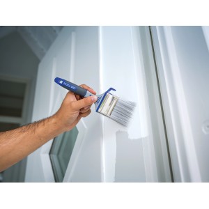 Hand streicht mit LUX Flachpinsel Lack 60mm eine weiße Tür. Pinsel mit Eimerhaken.