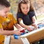 Kinder spielen am Axi Nick Sand- und Wasser-Picknicktisch Braun-Weiß mit blauen Wannen.