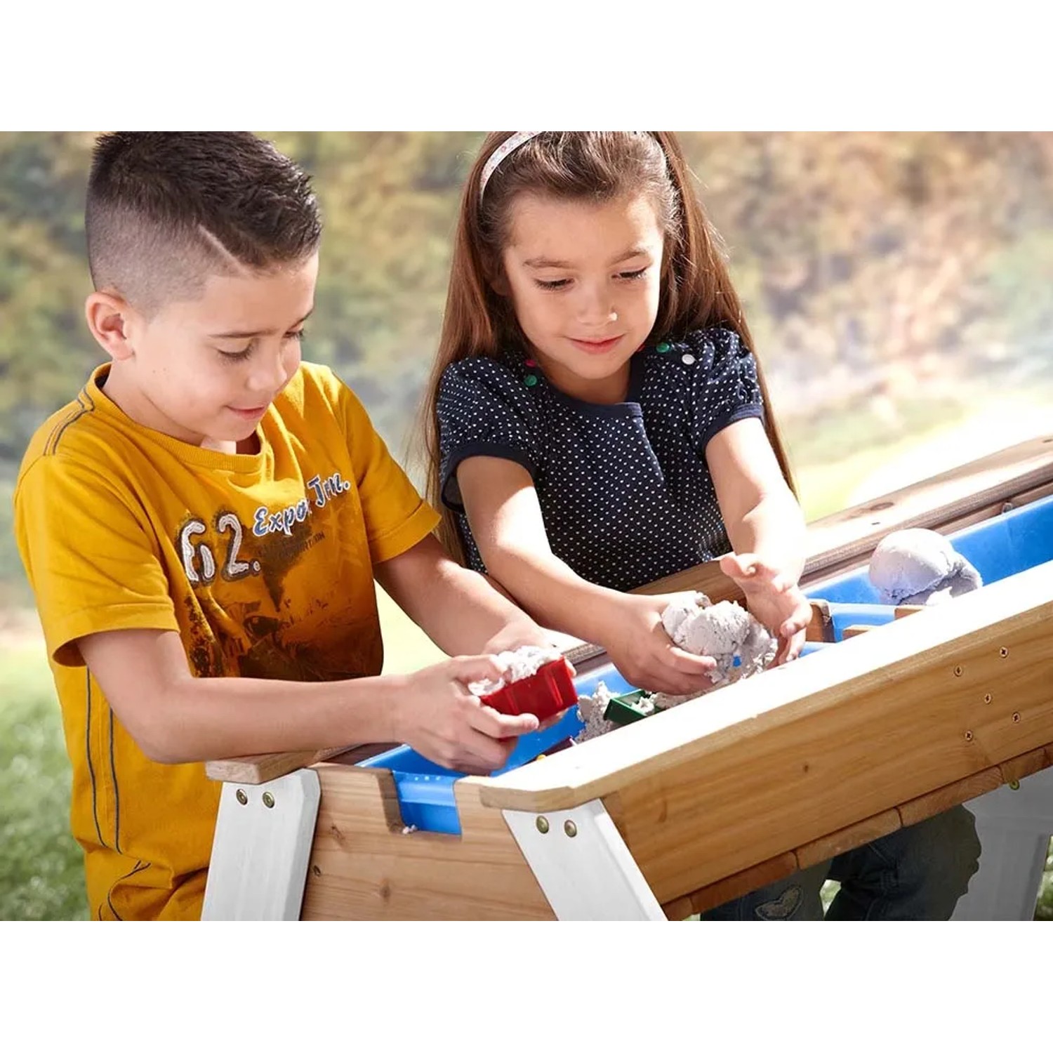 Kinder spielen am Axi Nick Sand- und Wasser-Picknicktisch Braun-Weiß mit blauen Wannen.