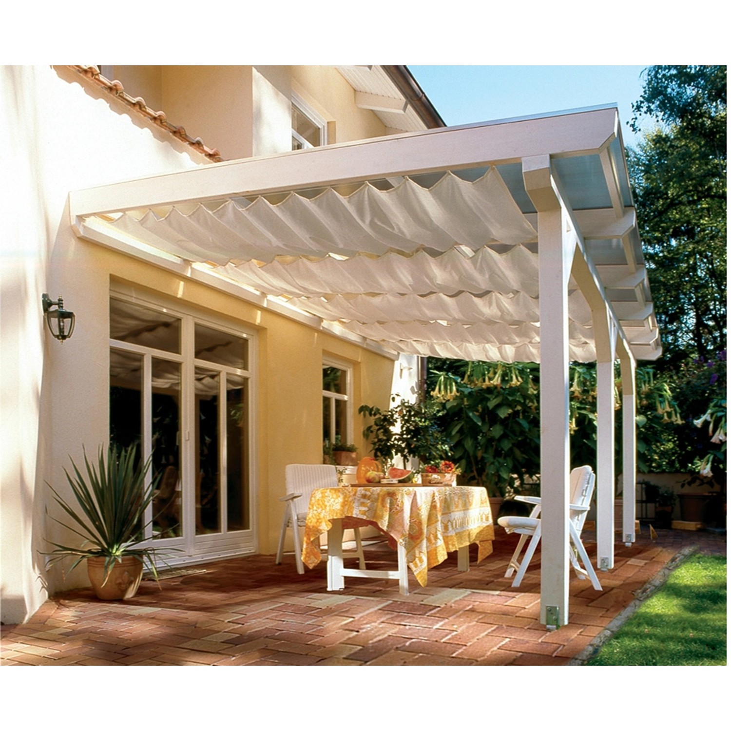 Weiße Skan Holz Terrassenüberdachung Andria mit Stoffbehang und Sitzgruppe auf Terrasse.