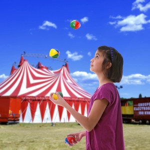 Mädchen jongliert bunte Jonglierbälle aus Kunststoff vor Zirkuszelt. 24er Set für Spiel & Spaß.