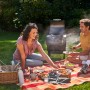 Paar grillt mit dem tragbaren Char-Broil Holzkohlegrill 2Go im Garten beim Picknick.