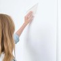 Frau glättet Vliestapete mit Werkzeug aus dem Wallpro Werkzeug-Set.