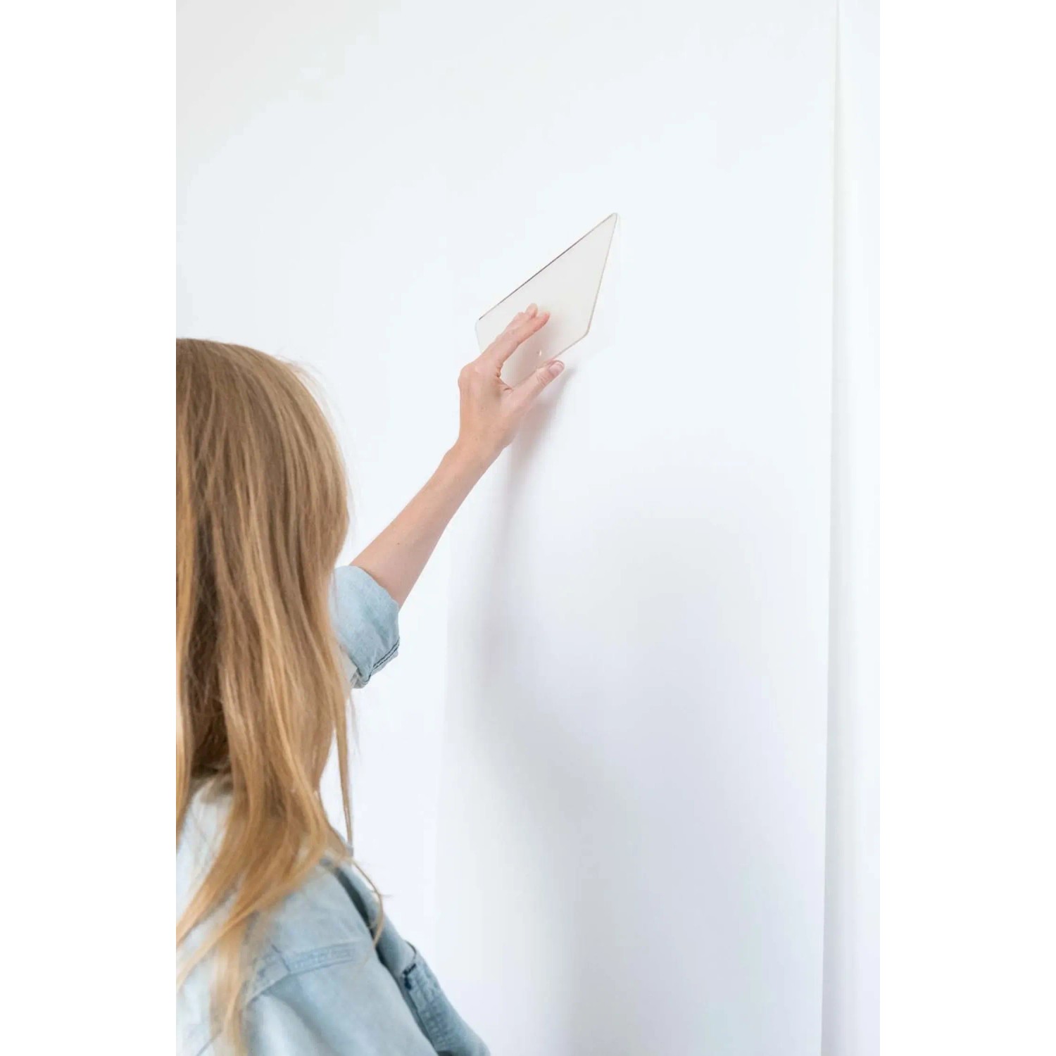 Frau glättet Vliestapete mit Werkzeug aus dem Wallpro Werkzeug-Set.