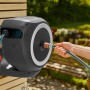 Gardena Wand-Schlauchbox RollUp S mit 15 m Schlauch im Einsatz, montiert an einer Holzwand.