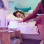 WiZ Hero LED-Tischleuchte in Weiß neben Kind im Bett, steuerbar per App.