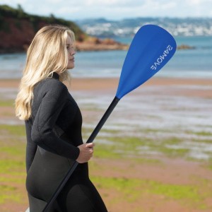 Frau mit blauem 24Move Doppelpaddel (230cm) für SUP-Board/Kajak am Strand.