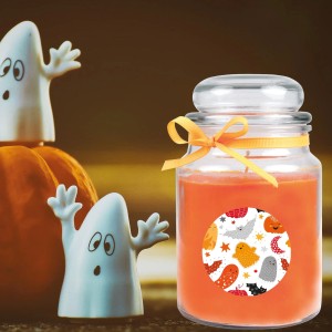 Orangefarbene Halloween Duftkerze im Glas mit Geister-Motiv und Deko.