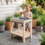 Lachendes Kind spielt mit Wasser am roba Outdoor Spiel- & Wassertisch aus Naturholz mit grauer Wanne auf der Terrasse.