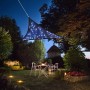 Dunkelblaues, dreieckiges Perel Sonnensegel mit LED-Beleuchtung über einer Gartensitzgruppe.