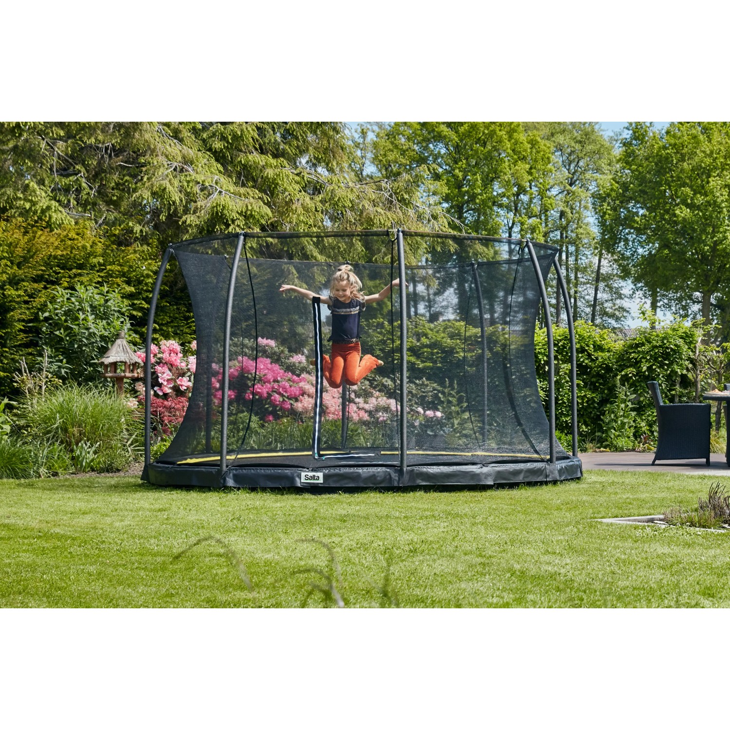 Schwarzes Salta Bodentrampolin Comfort Edition (ø 251 cm) mit Kind im Garten.