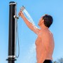 Bestway Solarflow Gartendusche mit 20 l Tank in Nutzung: Mann duscht unter blauem Himmel.