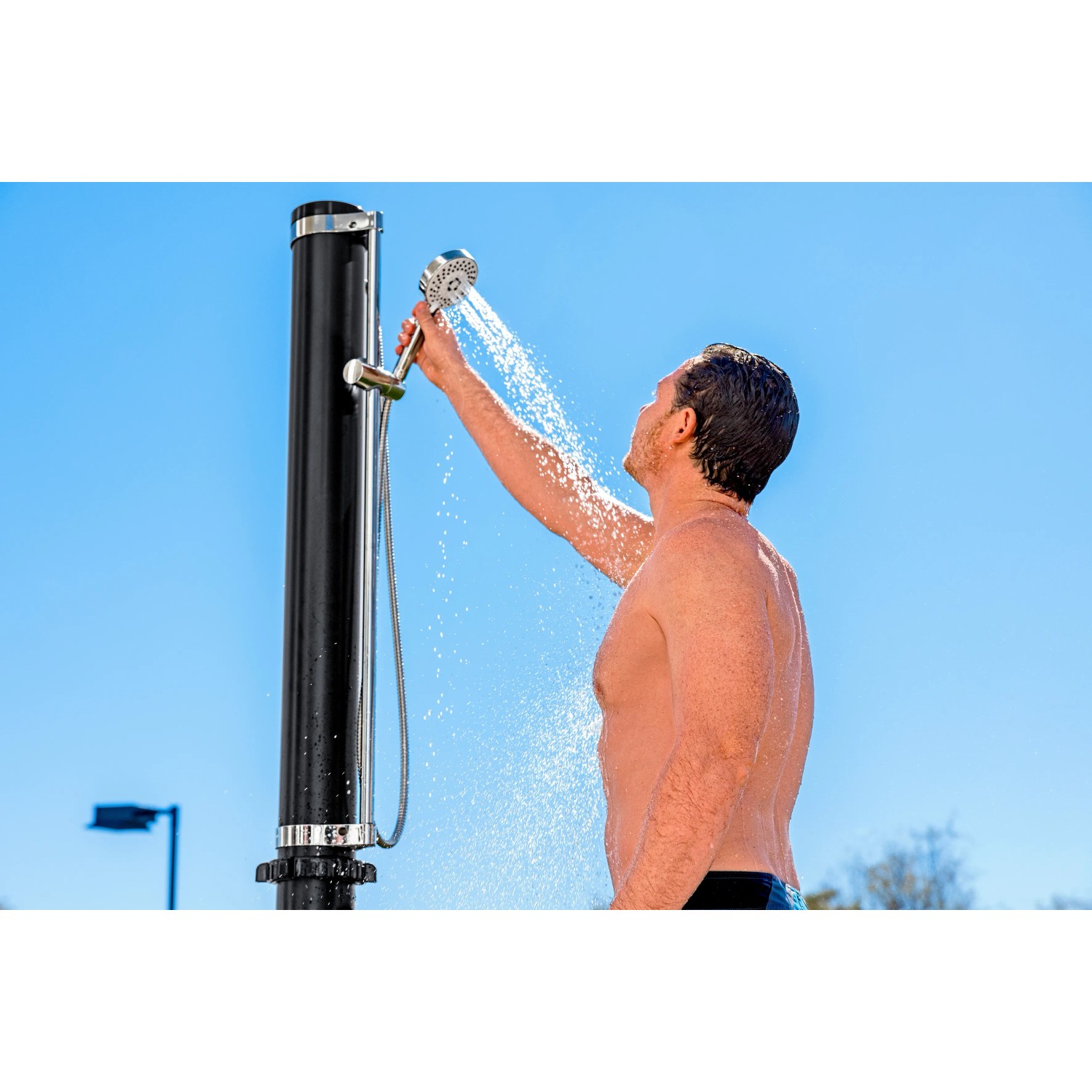 Bestway Solarflow Gartendusche mit 20 l Tank in Nutzung: Mann duscht unter blauem Himmel.