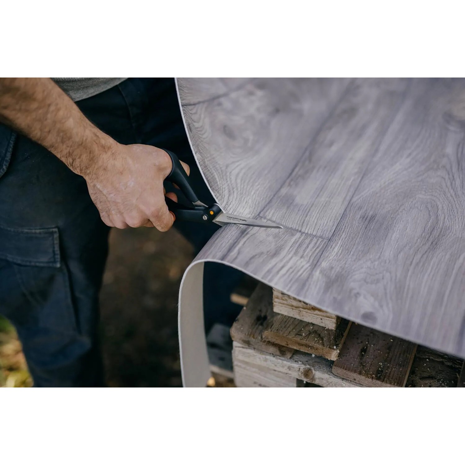 Zahnung der Fiskars Amplify Hardware-Schere schneidet grauen Vinylboden. Schere: 21 cm.