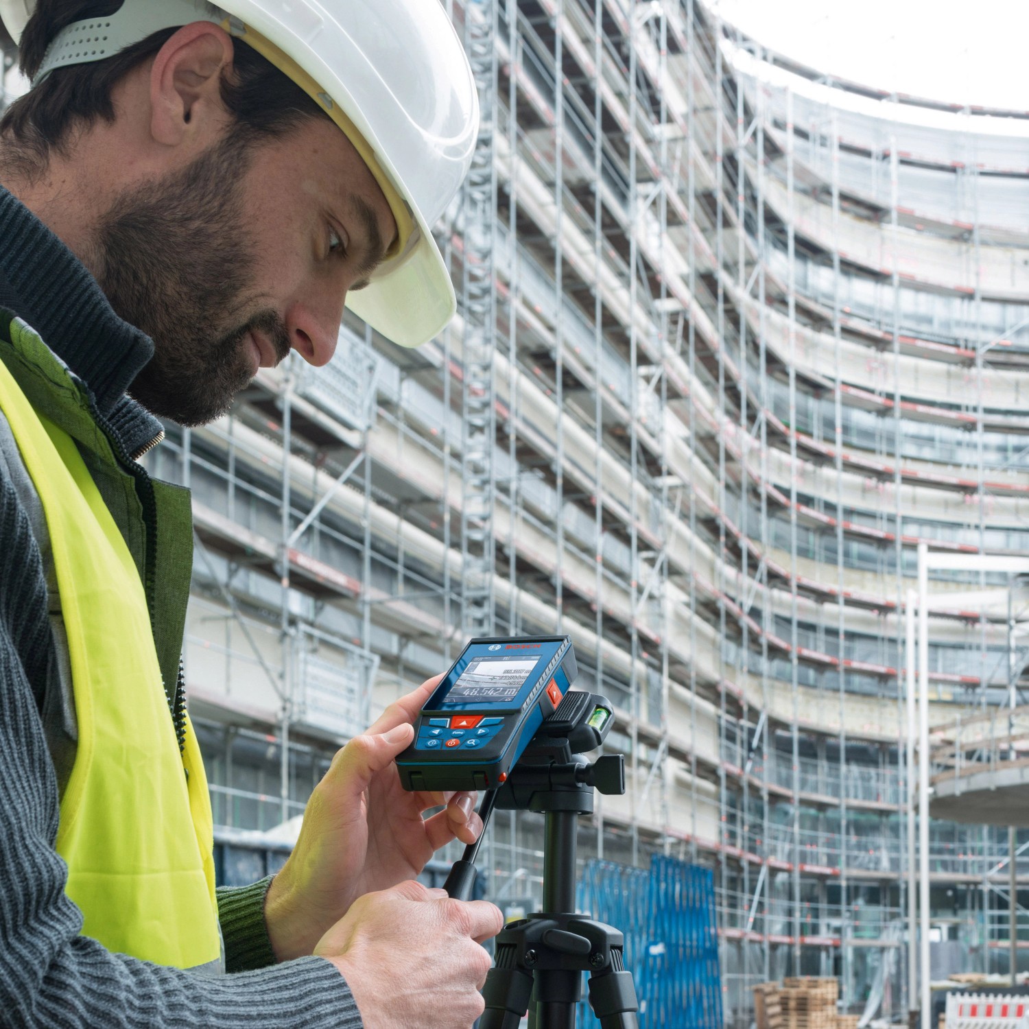 Bauarbeiter misst mit dem digitalen Bosch Professional Laser-Entfernungsmesser GLM 100-25 C auf einer Baustelle.
