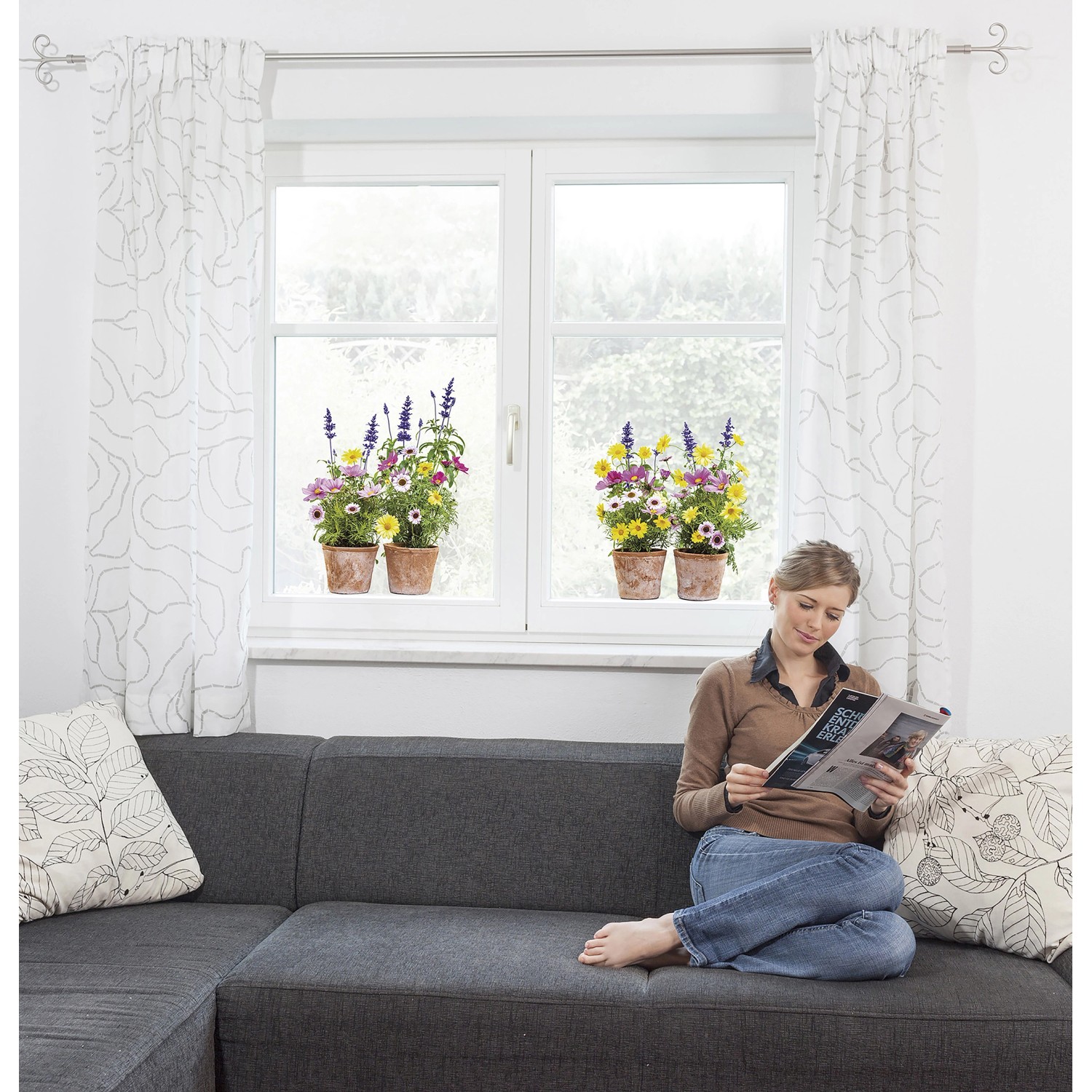 Komar Fenstersticker Springtime, 31x31 cm, mit bunten Blumenmotiven auf einem Fenster, Frau auf Sofa.