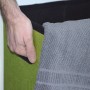 Grüner, faltbarer Wäschekorb (70L) in Leinen-Optik mit Hand und grauem Handtuch.