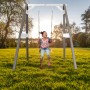 Axi Einzelschaukel Grau-Weiß mit Kind im Garten. Holzschaukel für Balance und Spaß.