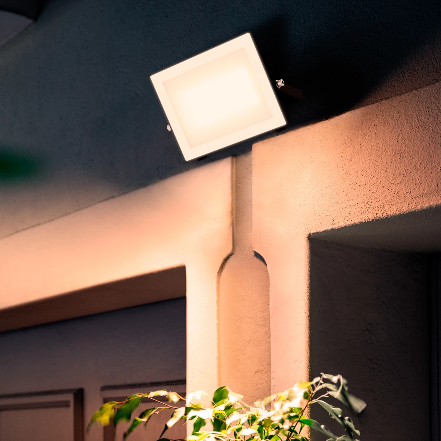 Schwarzer Philips LED-Außenstrahler Lois mit 4.500 lm und warmweißem Licht an einer Hauswand.