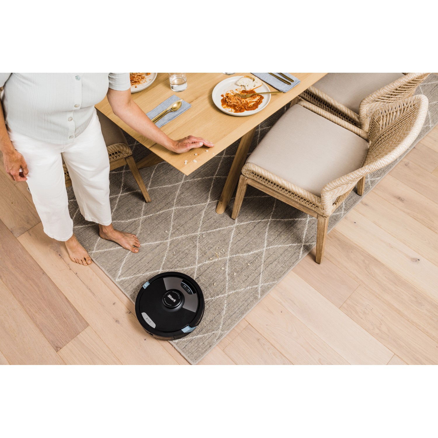 Schwarzer Shark Saug- und Wischroboter Matrix Plus RV2620WDEU im Einsatz unter Esstisch.