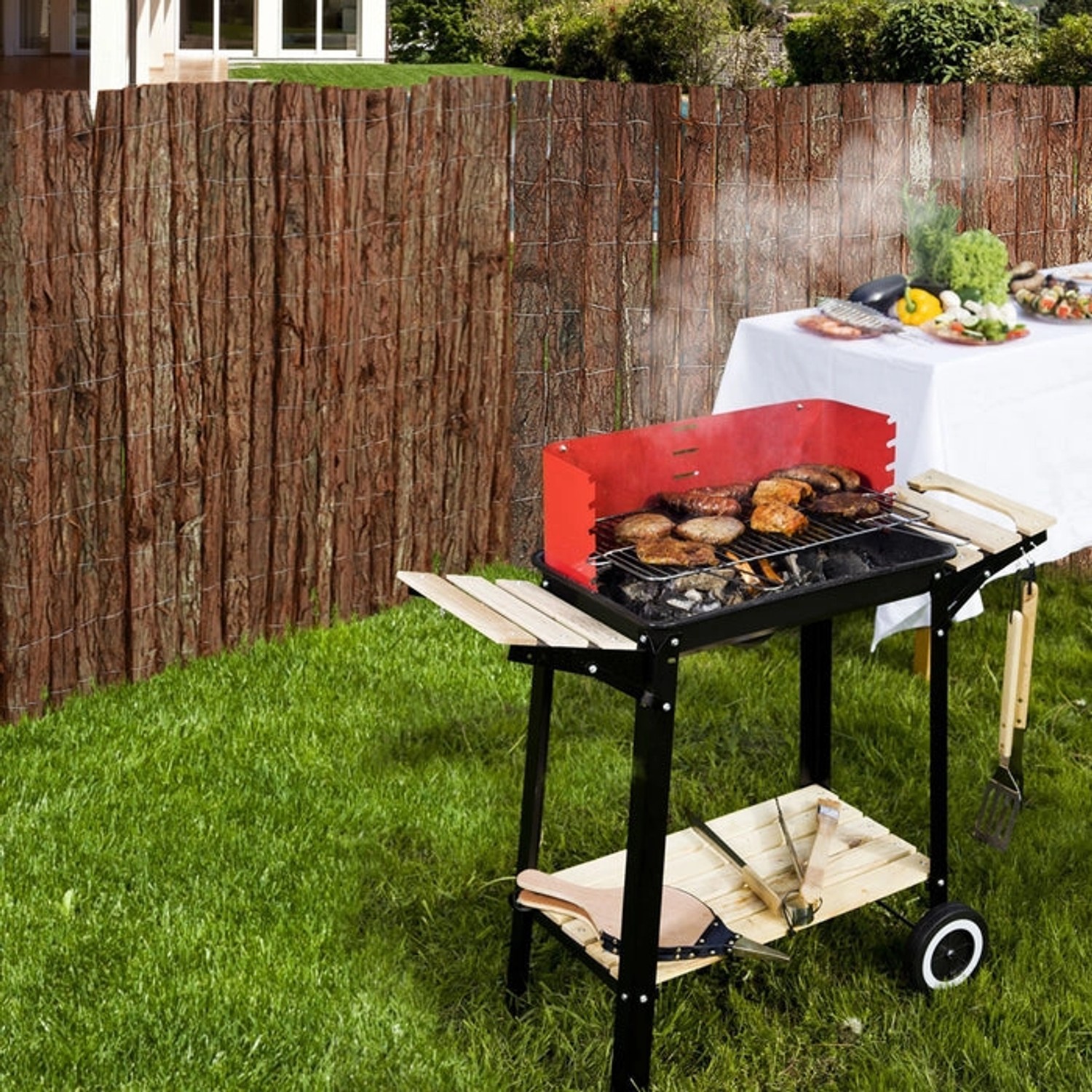 KARAT Baumrindenmatte als Sichtschutz im Garten, kombiniert mit Grill und Gartentisch.