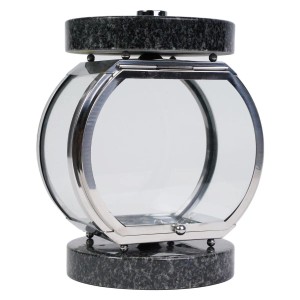 Rundliche Grablampe aus dunklem Granit und glänzendem Edelstahl mit klaren Glasscheiben und Tür.